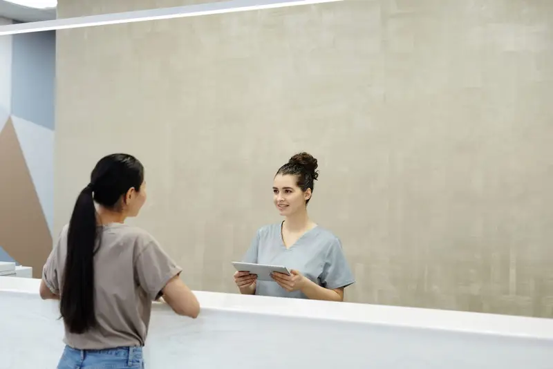 Medizinische Fachangestellte begrüßt eine Patientin am Empfang