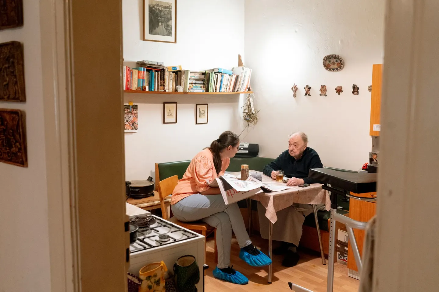 Junge Frau und älterer Mann sitzen gemeinsam am Tisch und lesen