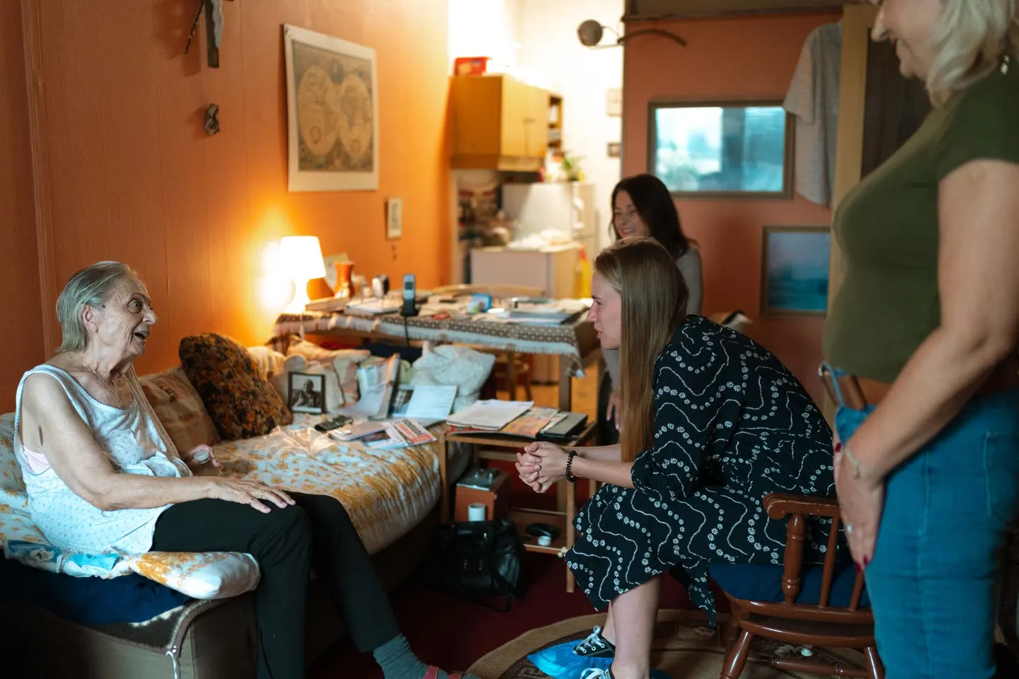 Beraterin spricht mit einer älteren Frau und Angehörigen im Wohnzimmer
