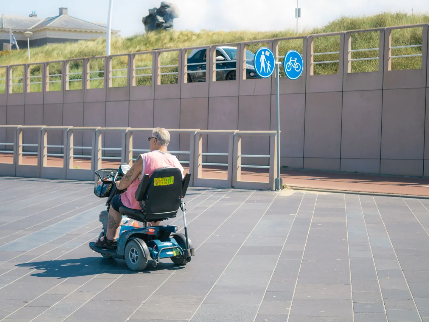 Mann fährt mit einem Elektromobil an einer Promenade entlang